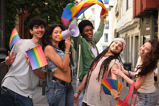 istock Young activists marching for LGBT rights waving rainbow flags and using megaphone 2207619479