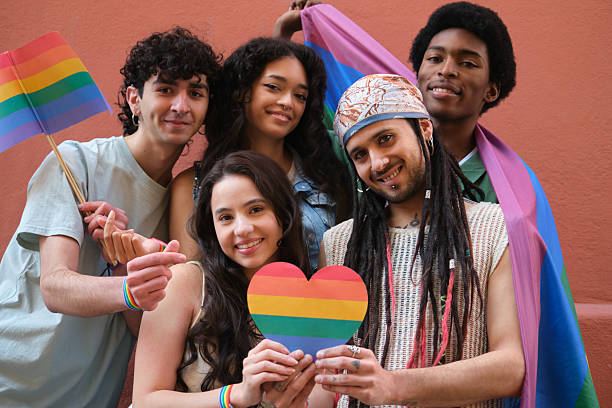 istock Young activists holding rainbow heart and flags celebrating gay pride 2207620969