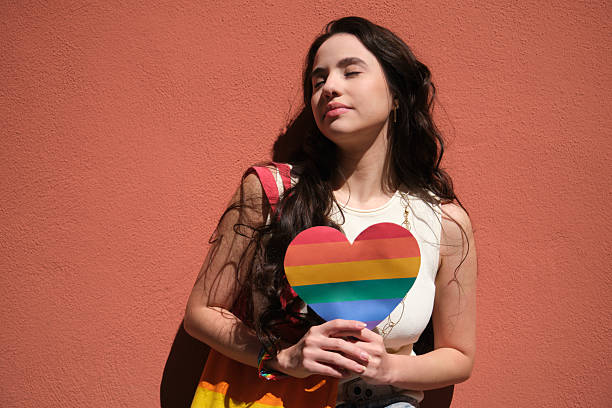 Young woman holding a rainbow heart celebrating pride