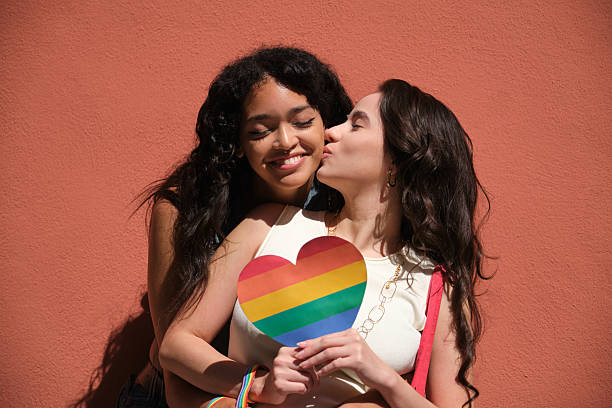 istock Two young women embracing and holding a rainbow heart 2207622661