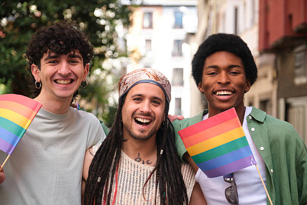 istock Three Young Men Smiling and Holding Rainbow Flags at Pride Parade 2207623169