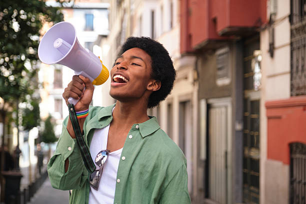 Young activist is using a megaphone at a LGBT pride parade
