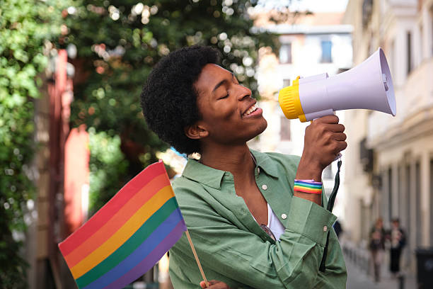 istock Young activist speaking with megaphone at lgbt pride parade 2207624942