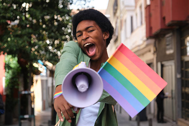 istock Young activist shouting with megaphone at a LGBT pride parade 2207625027