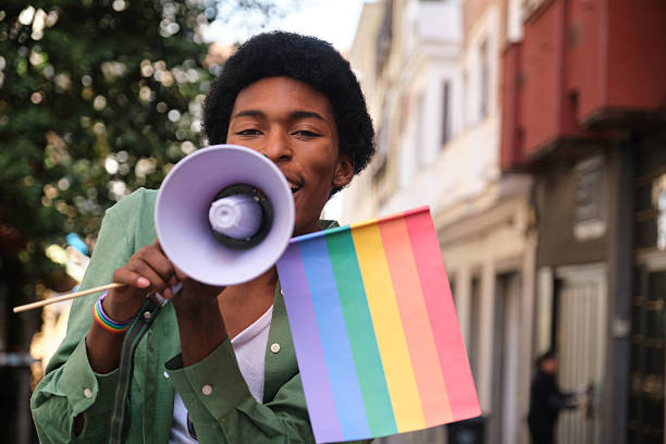 istock Young man speaking with megaphone at LGBT pride parade 2207625067
