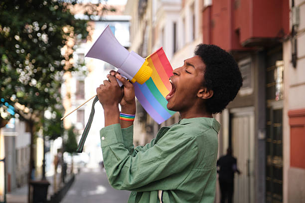 istock Young man shouting with megaphone at a LGBT pride parade 2207625102