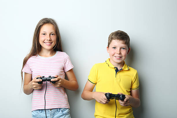istock Young boy and girl with joysticks on grey background 2207628606