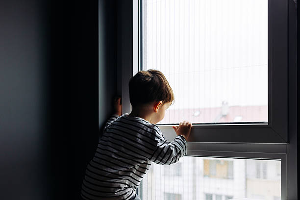 istock Curious child looking out the window at home 2207633211