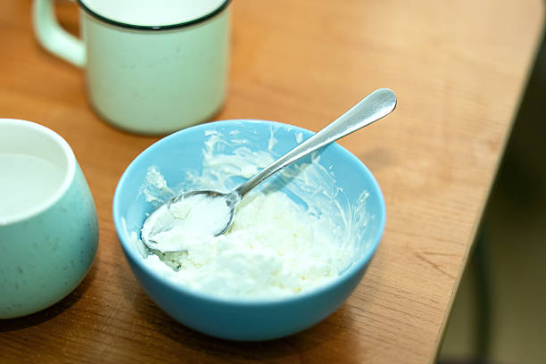 ceramic blue bowl filled with fresh cottage cheese, accompanied by a spoon, perfect for a healthy breakfast. Ideal for food photography and culinary inspiration