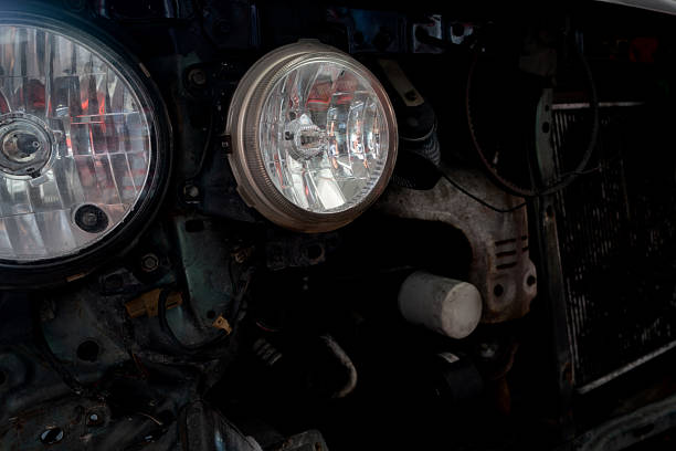 istock Front view of a car in a workshop with its bumper and grille removed, exposing two circular headlights and a central radiator. 2207634409