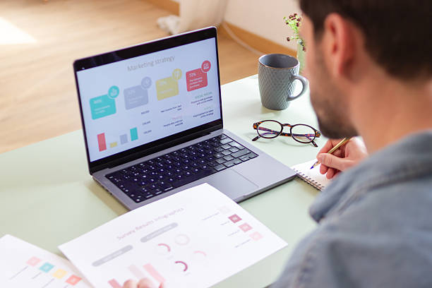 istock Marketing manager working at home analyzing marketing strategy on laptop and taking notes 2207636697