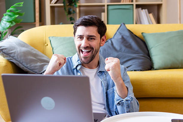 istock Excited young man celebrating success while working from home 2207637460