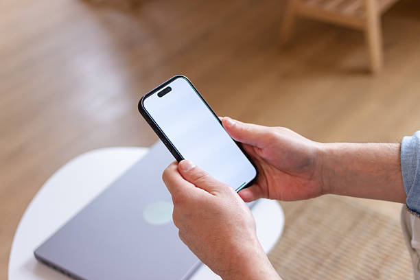istock Businessman using smartphone with blank screen next to laptop 2207637682