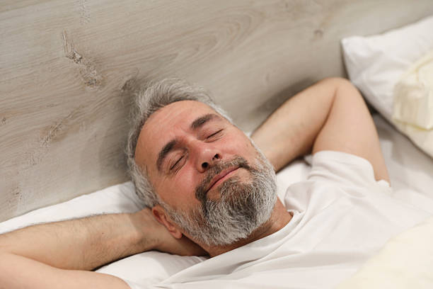 Tranquil Rest: Man Wears Eye Mask and Earplugs in Bed for Enhanced Sleep Quality