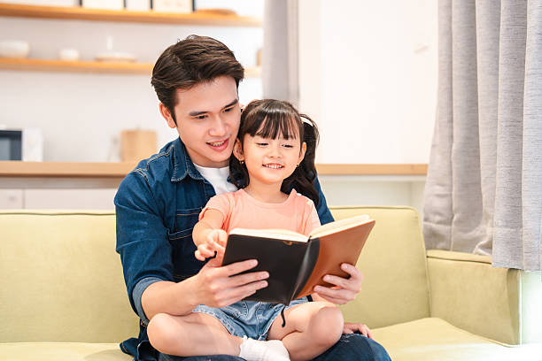 istock Father and Daughter Reading Together on a Sofa in a Bright Home Sharing a Special Bond 2207643229