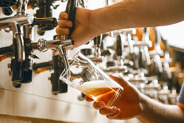 istock Pouring Refreshing Beer From Tap Into Glass at Bustling Bar During Evening 2207645405
