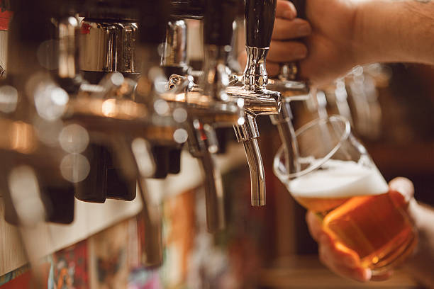 istock Bartender Pours Golden Beer Into Glass While Serving at Lively Bar 2207645435