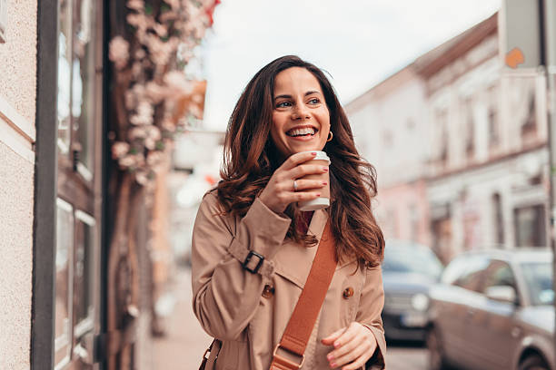 istock Happy young woman drinking coffee while walking in the city 2207646589