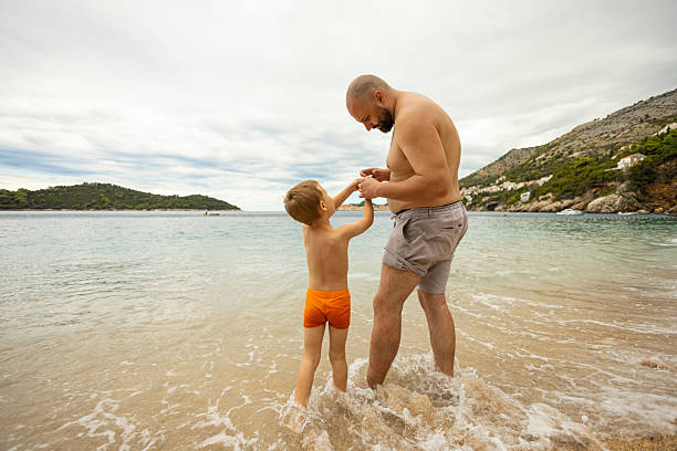 Father and his son playing and exploring at the sea beach