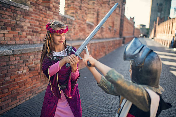 istock Little princess practicing swordplay with a little knight on the medieval bridge 2207649465