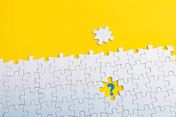 istock A white jigsaw puzzle on yellow background. A piece is missing in the center, with a blue question mark, a puzzle piece placed above, symbolizing problem-solving or searching for the right fit. 2207650208