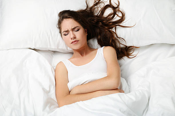 istock Sick young woman lying in white bed 2207650339