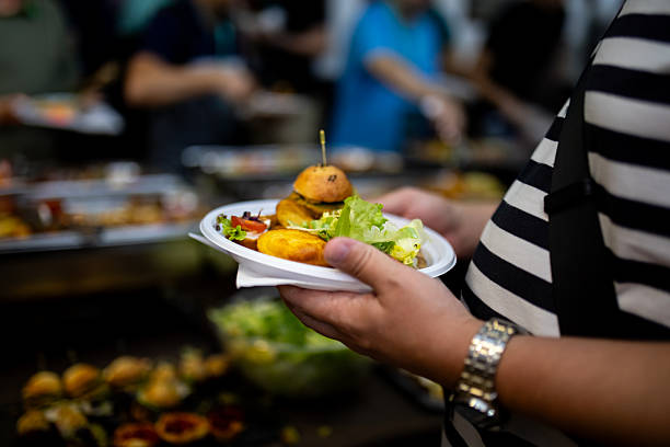 istock Plate of food held by a diner at a bustling communal dining event in a lively setting 2207650989