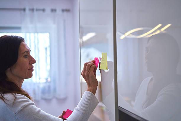 istock Putting Adhesive Notes on Refrigirator with a Shopping List and Organizing Household Notes 2207653376