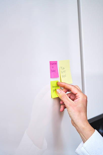istock Putting Adhesive Notes on Refrigirator with a Shopping List and Organizing Household Notes 2207653728