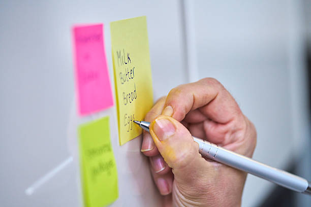 istock Writting Shopping List on Adhesive Note and Putting on Refrigirator 2207654080