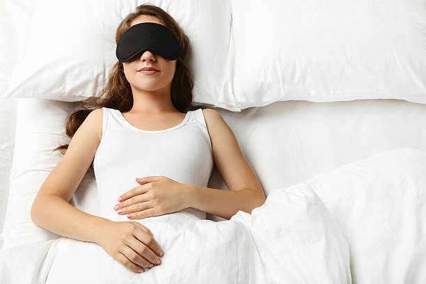istock Young woman sleeping with eyemask in white bed 2207655516