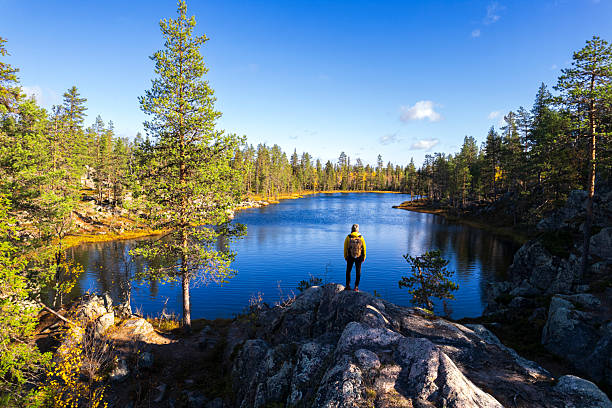 Hiker in the forest admires alpine lake