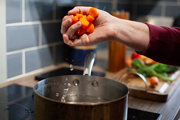 istock dropping sliced carrots into a saucepan 2207657665