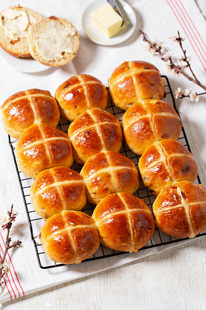 istock Hot cross buns served with butter and blossoming apricot branches. 2207664301