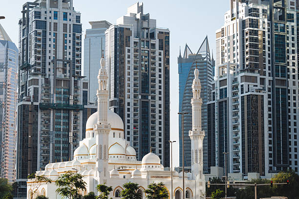 Traditional minaret of the mosque against modern buildings in Abu Dhabi, uAE. High quality photo.