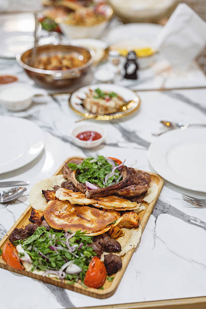 A vibrant Middle Eastern feast featuring grilled meats, fresh vegetables, and flatbreads served on a marble table. The meal includes flavorful spices and diverse textures, perfect for savoring culinary traditions in a warm dining setting.