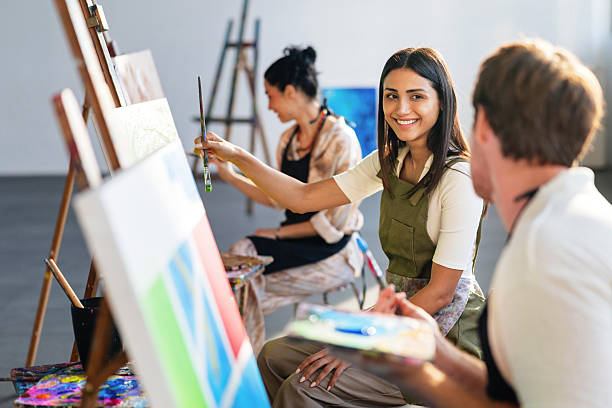 istock Young Artists In Green Aprons Working At Easels During Creative Painting Class 2207667115
