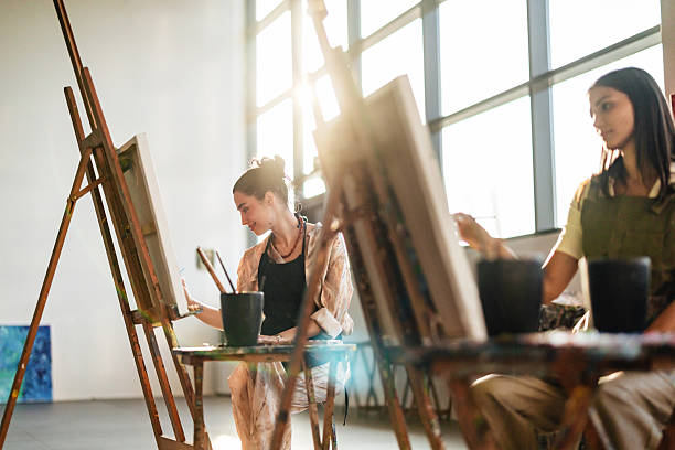 istock Young Middle Eastern Artists In Black Aprons Paint At Sunlit Studio Easels 2207667128