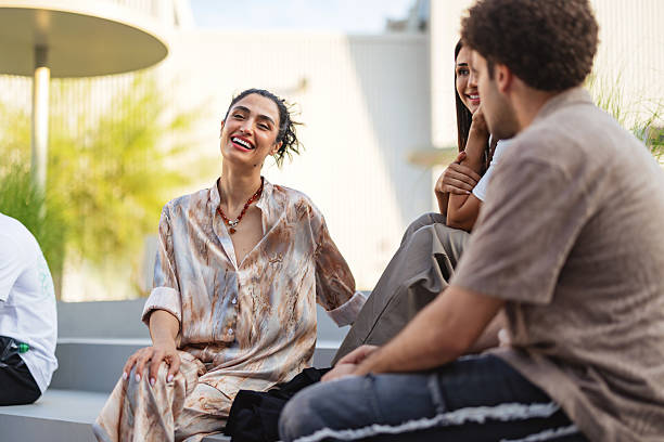istock Multicultural Friends Sharing Laughter in Modern Dubai Setting, Young Woman in Marble-Pattern Silk Blouse 2207667246