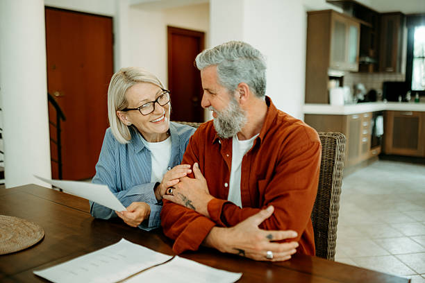 istock Casually clothed mature couple reviewing documents together at home 2207667631