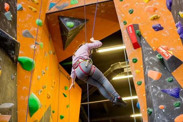 fitness, extreme sport, bouldering, people and healthy lifestyle concept - young girl exercising at indoor climbing gym