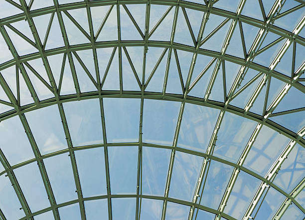 istock Modern glass roof structure featuring intricate metal framework and clear blue sky during midday sunlight in an urban setting 2207673489
