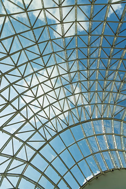 istock Modern glass roof structure featuring intricate metal framework and clear blue sky during midday sunlight in an urban setting 2207673503