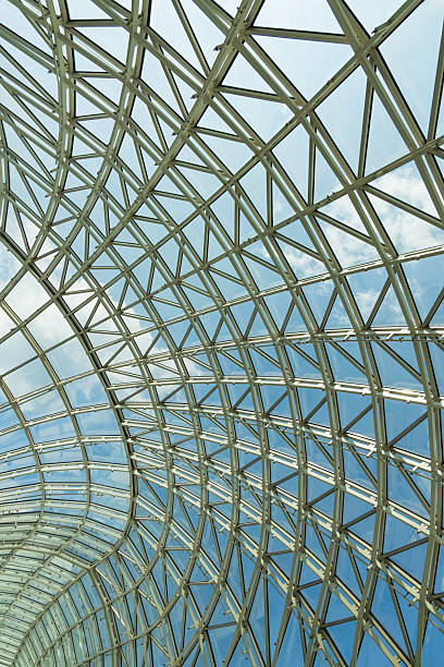 istock Modern glass roof structure featuring intricate metal framework and clear blue sky during midday sunlight in an urban setting 2207673516