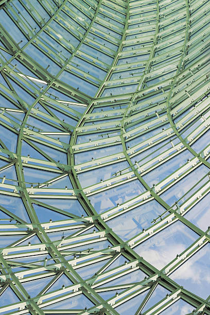 istock Modern glass roof structure featuring intricate metal framework and clear blue sky during midday sunlight in an urban setting 2207673522