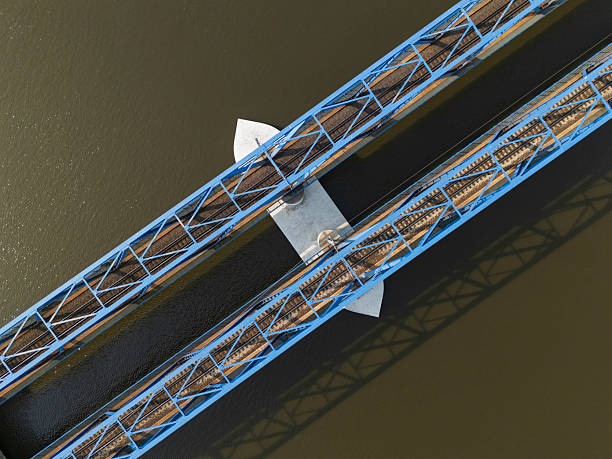 A well-structured blue metal bridge spans over a body of water, displaying intricate details of rail tracks positioned below. The view highlights modern engineering.