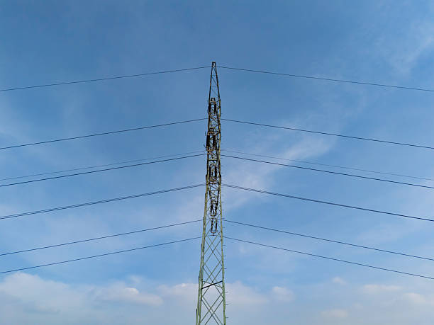 Steel power tower stands tall against a cloudy sky with electric lines extending in multiple directions, representing critical energy transmission infrastructure in an open landscape.