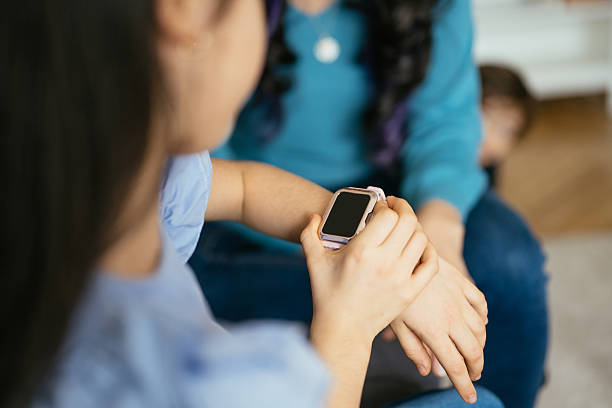 Children using smartwatch supervised by parents at home