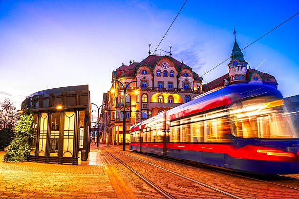 fotografii de stoc, fotografii și imagini scutite de redevențe cu oradea, românia: tramvaiul de dimineață în mișcare în piața unirii, cu arhitectura frumoasă a orașului crișana, transilvania, cerul colorat al răsăritului - bihor