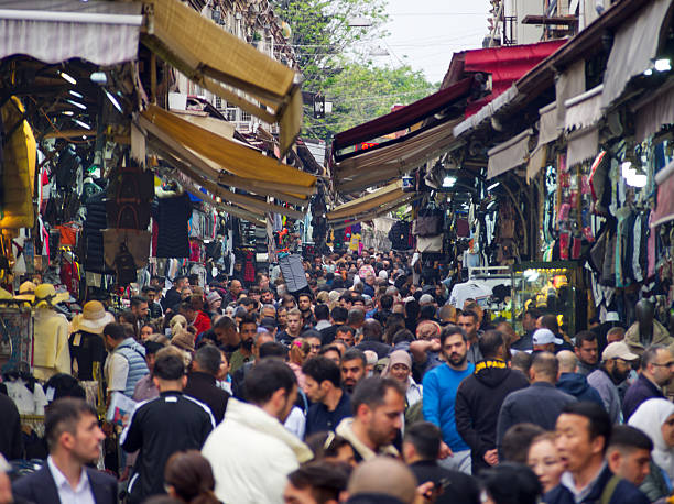 Istanbul, Turkey - May 2, 2024: Bustling market street filled with people, lined with stalls and colorful awnings overhead